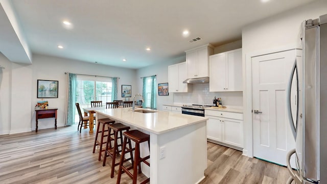 3428 Pepper Glendale Dr, Murfreesboro, TN 37128 - kitchen with fridge, under cabinet range hood, light wood-type flooring, a kitchen bar, and tasteful backsplash