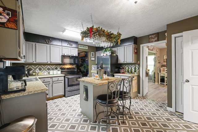 144 Waggoner St, Carthage, TN 37030 - kitchen with stainless steel appliances, a center island, backsplash, a kitchen breakfast bar, and a textured ceiling