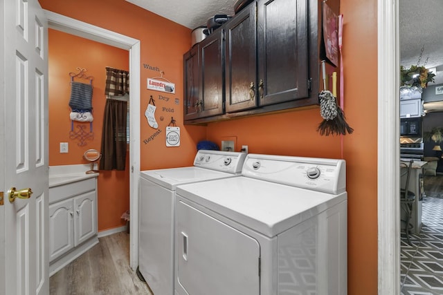 144 Waggoner St, Carthage, TN 37030 - laundry area with cabinet space, washing machine and clothes dryer, a textured ceiling, and light wood-style flooring