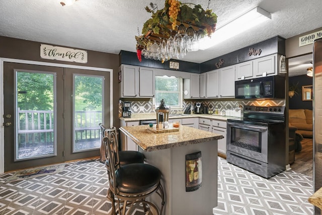 144 Waggoner St, Carthage, TN 37030 - kitchen featuring stainless steel electric range oven, black microwave, a textured ceiling, backsplash, and a kitchen bar