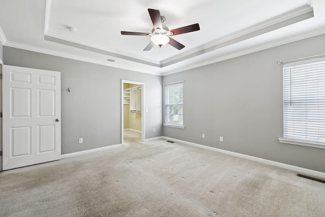6014 Thrush Ct, Spring Hill, TN 37174 - unfurnished bedroom featuring a tray ceiling, crown molding, a walk in closet, light colored carpet, and a ceiling fan