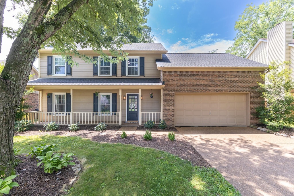 538 Maplegrove Dr, Franklin, TN 37064 - view of front facade with driveway, brick siding, an attached garage, a porch, and a front lawn