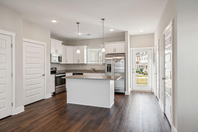 7026 Magnolia Crossings, Spring Hill, TN 37174 - kitchen featuring appliances with stainless steel finishes, a kitchen island, white cabinetry, dark wood finished floors, and decorative light fixtures