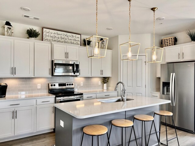 1000 June Wilde Rdg, Spring Hill, TN 37174 - kitchen featuring appliances with stainless steel finishes, light wood-style floors, backsplash, a breakfast bar area, and white cabinetry