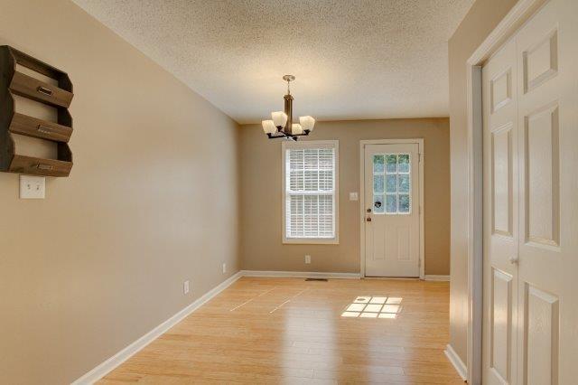 421 Woodale Dr, Clarksville, TN 37042 - unfurnished dining area with a chandelier, a textured ceiling, and light wood-type flooring
