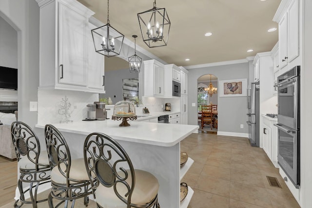 2005 Windsong Dr, Spring Hill, TN 37174 - kitchen with a chandelier, arched walkways, appliances with stainless steel finishes, a breakfast bar, and backsplash