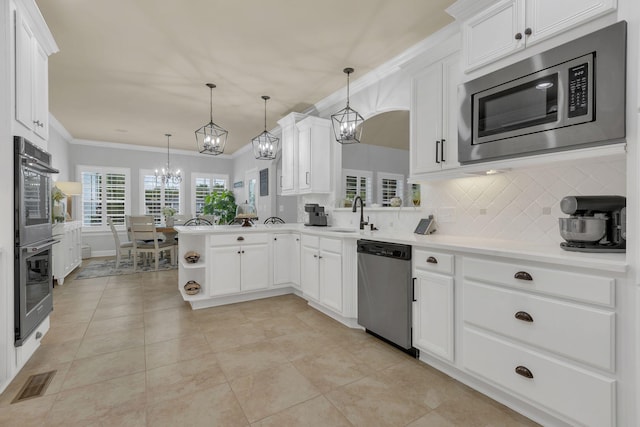 2005 Windsong Dr, Spring Hill, TN 37174 - kitchen featuring appliances with stainless steel finishes, a chandelier, backsplash, white cabinetry, and crown molding