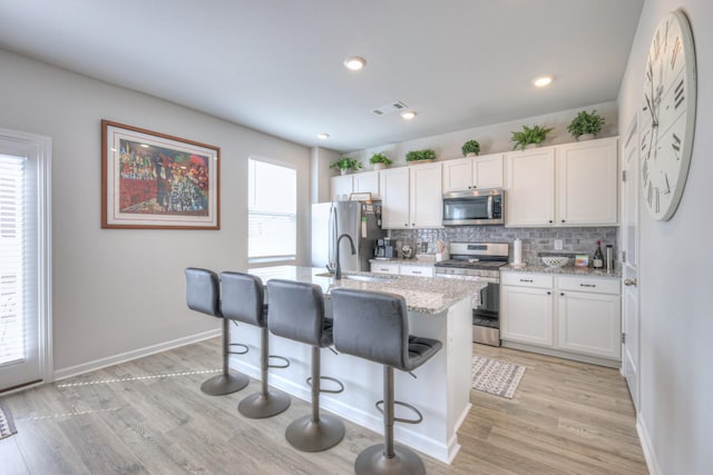207 Welara St, Murfreesboro, TN 37129 - kitchen featuring stainless steel appliances, backsplash, an island with sink, light wood finished floors, and recessed lighting