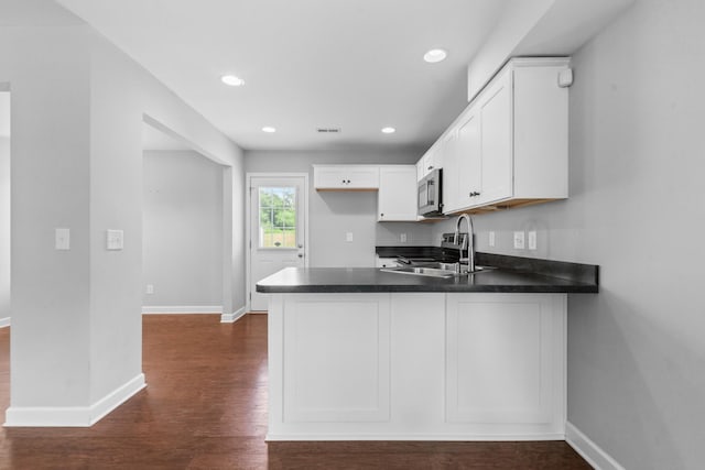 109 Tindell Ln, Columbia, TN 38401 - kitchen with appliances with stainless steel finishes, a peninsula, dark countertops, dark wood-style flooring, and white cabinets