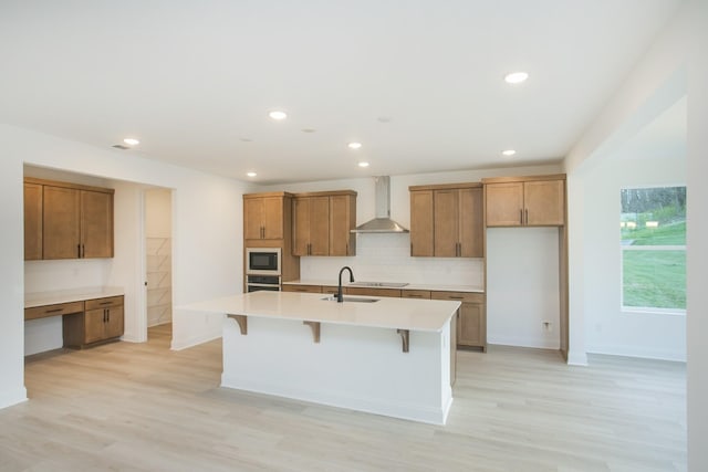 2359 Williamsport Lndg, Columbia, TN 38401 - kitchen with wall chimney range hood, built in microwave, tasteful backsplash, brown cabinets, and a center island with sink