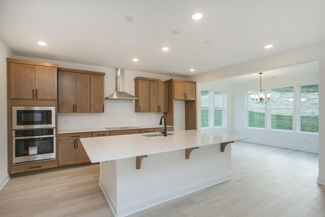2359 Williamsport Lndg, Columbia, TN 38401 - kitchen with appliances with stainless steel finishes, wall chimney exhaust hood, an island with sink, light wood finished floors, and light countertops