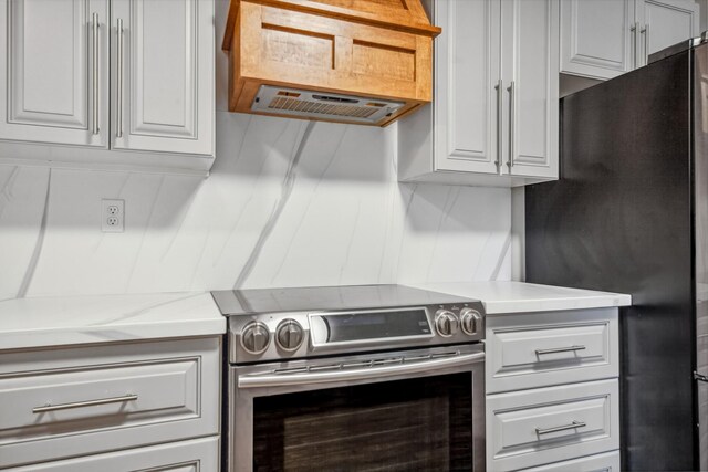 116 Skyview Dr, Columbia, TN 38401 - kitchen featuring stainless steel electric range, freestanding refrigerator, light countertops, extractor fan, and white cabinets