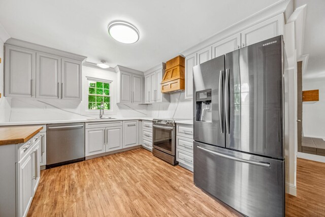 116 Skyview Dr, Columbia, TN 38401 - kitchen featuring appliances with stainless steel finishes, premium range hood, light wood-style flooring, and wooden counters