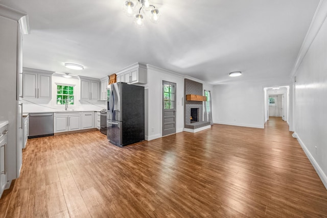 116 Skyview Dr, Columbia, TN 38401 - unfurnished living room featuring wood finished floors, a fireplace, ornamental molding, and a chandelier