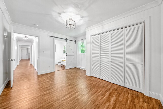 116 Skyview Dr, Columbia, TN 38401 - unfurnished bedroom with ornamental molding, a barn door, light wood-style floors, a closet, and a chandelier