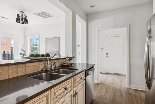 140 Ormesby Pl, Franklin, TN 37064 - kitchen with dark countertops, appliances with stainless steel finishes, wood finished floors, cream cabinetry, and crown molding