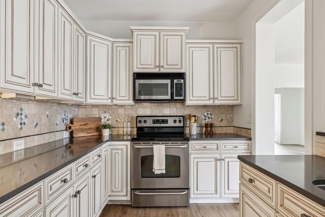 140 Ormesby Pl, Franklin, TN 37064 - kitchen featuring stainless steel appliances, dark countertops, tasteful backsplash, and light wood-style flooring