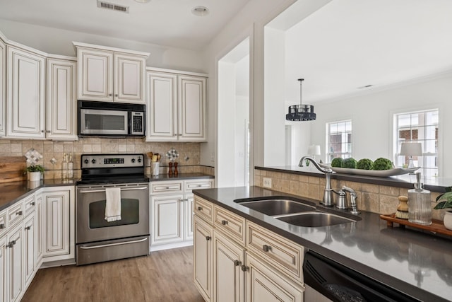 140 Ormesby Pl, Franklin, TN 37064 - kitchen with appliances with stainless steel finishes, dark countertops, backsplash, light wood-style floors, and ornamental molding