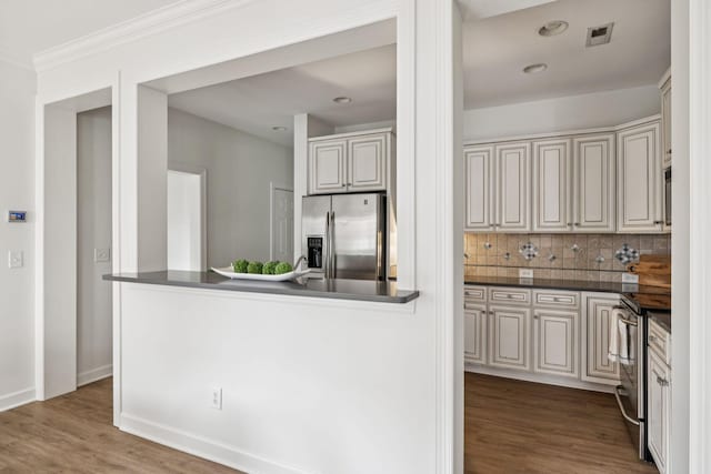 140 Ormesby Pl, Franklin, TN 37064 - kitchen featuring appliances with stainless steel finishes, dark countertops, backsplash, wood finished floors, and ornamental molding