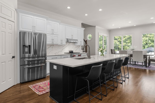 5605 Ottershaw Ct, Brentwood, TN 37027 - kitchen with stainless steel fridge, under cabinet range hood, light stone counters, backsplash, and white cabinets