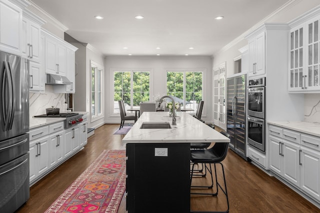5605 Ottershaw Ct, Brentwood, TN 37027 - kitchen with appliances with stainless steel finishes, dark wood-style floors, white cabinets, a center island with sink, and tasteful backsplash