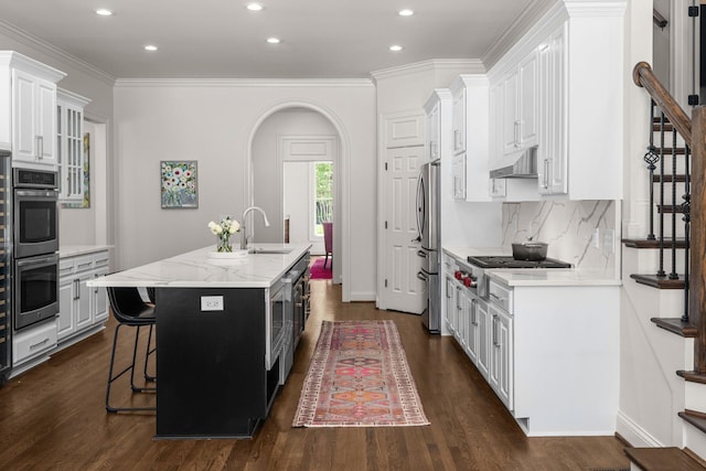 5605 Ottershaw Ct, Brentwood, TN 37027 - kitchen with arched walkways, a breakfast bar, a kitchen island with sink, white cabinets, and recessed lighting