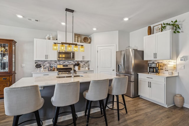 2410 Tate Farm Ln, White House, TN 37188 - kitchen featuring stainless steel appliances, tasteful backsplash, light countertops, a center island with sink, and a kitchen bar