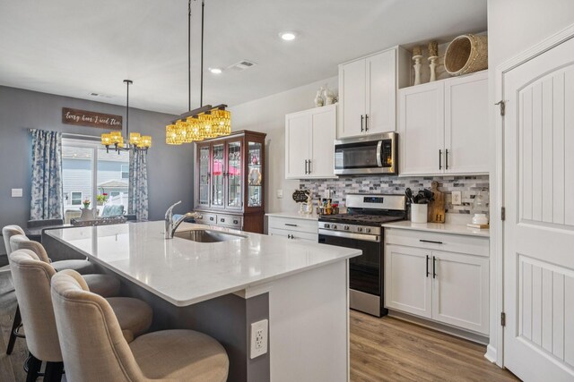 2410 Tate Farm Ln, White House, TN 37188 - kitchen with stainless steel appliances, wood finished floors, backsplash, a chandelier, and white cabinets