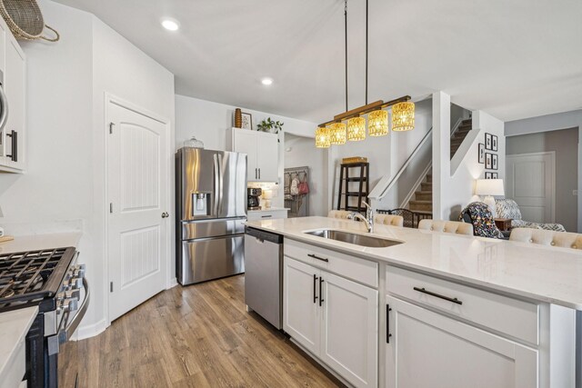 2410 Tate Farm Ln, White House, TN 37188 - kitchen with appliances with stainless steel finishes, white cabinetry, wood finished floors, decorative light fixtures, and recessed lighting
