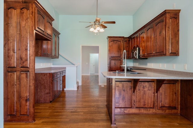 717 Pleasant View Dr, Columbia, TN 38401 - kitchen with stainless steel microwave, a ceiling fan, a peninsula, dark wood-style flooring, and a high ceiling