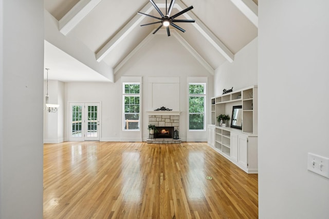 4019 Fremantle Cir, Spring Hill, TN 37174 - unfurnished living room featuring light wood-style floors, ceiling fan, high vaulted ceiling, a stone fireplace, and beamed ceiling