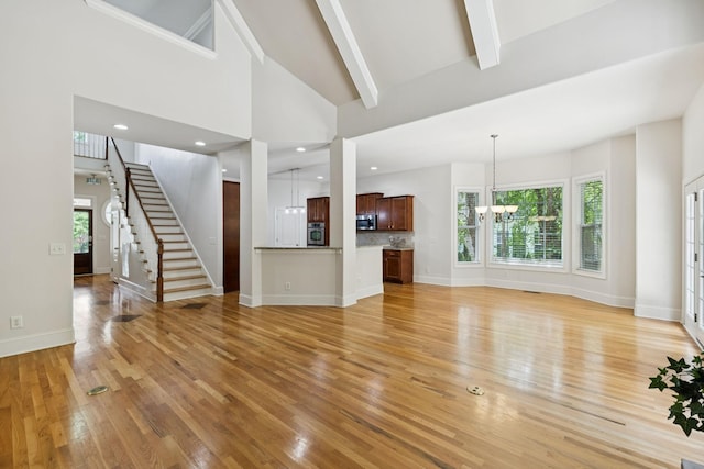 4019 Fremantle Cir, Spring Hill, TN 37174 - unfurnished living room with a chandelier, light wood-type flooring, healthy amount of natural light, beam ceiling, and stairs