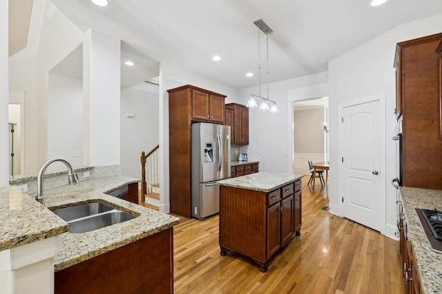 4019 Fremantle Cir, Spring Hill, TN 37174 - kitchen featuring appliances with stainless steel finishes, light wood-style flooring, a kitchen island, pendant lighting, and light stone counters