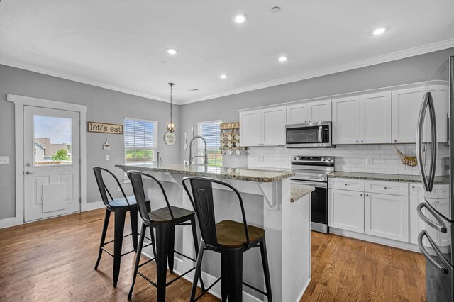 1021 Tulip Dr, Ashland City, TN 37015 - kitchen with appliances with stainless steel finishes, a center island with sink, light stone countertops, decorative backsplash, and white cabinetry