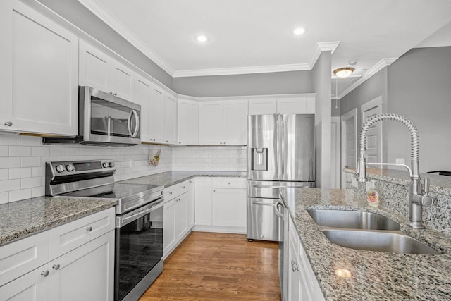 1021 Tulip Dr, Ashland City, TN 37015 - kitchen featuring appliances with stainless steel finishes, ornamental molding, white cabinetry, light wood-style flooring, and light stone counters