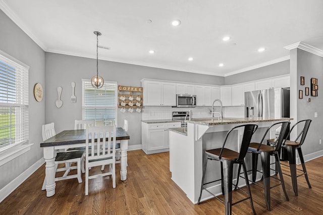 1021 Tulip Dr, Ashland City, TN 37015 - kitchen featuring stainless steel appliances, a kitchen island with sink, white cabinetry, light stone countertops, and crown molding
