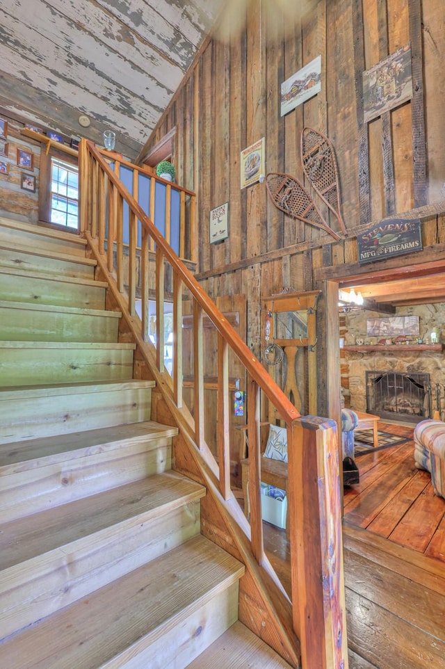569 Hogans Branch Rd, Hendersonville, TN 37075 - stairway featuring wood walls, a fireplace, hardwood / wood-style flooring, and high vaulted ceiling