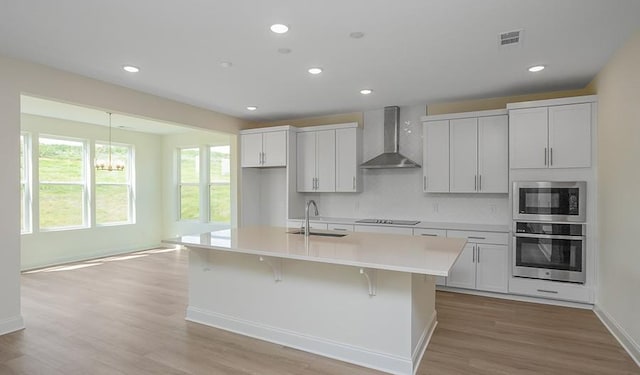 2901 Windstone Trl, Columbia, TN 38401 - kitchen with stainless steel appliances, wall chimney exhaust hood, a kitchen island with sink, decorative backsplash, and light countertops