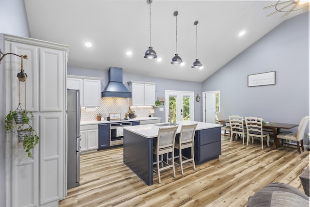 1567 Oak Knob Rd, Lafayette, TN 37083 - kitchen with custom exhaust hood, stainless steel appliances, vaulted ceiling, a kitchen island with sink, and light countertops