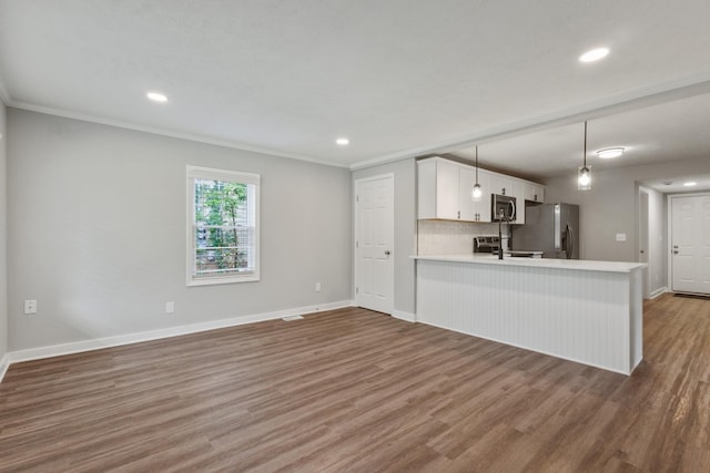 706 Poplar Ave, Murfreesboro, TN 37130 - kitchen with stainless steel appliances, light countertops, crown molding, wood finished floors, and recessed lighting