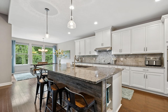 2229 Arbor Pointe Way, Hermitage, TN 37076 - kitchen featuring under cabinet range hood, backsplash, white cabinetry, an island with sink, and light stone countertops