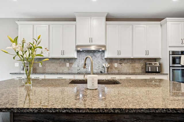 2229 Arbor Pointe Way, Hermitage, TN 37076 - kitchen with under cabinet range hood, double oven, decorative backsplash, and white cabinets