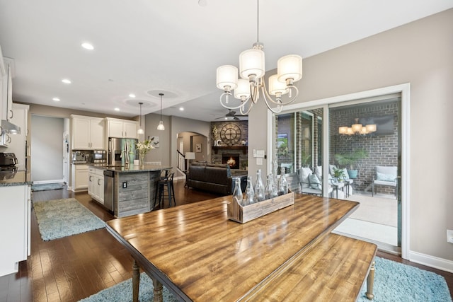 2229 Arbor Pointe Way, Hermitage, TN 37076 - dining space featuring arched walkways, dark wood-style flooring, a chandelier, a fireplace, and recessed lighting