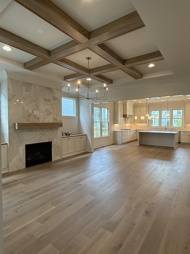 8007 Southvale Blvd, Franklin, TN 37064 - unfurnished living room with a chandelier, coffered ceiling, light wood-style flooring, a high end fireplace, and beamed ceiling