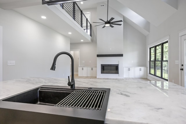 106 5th Ave N, Decherd, TN 37324 - kitchen featuring a towering ceiling, a glass covered fireplace, light stone countertops, open floor plan, and recessed lighting