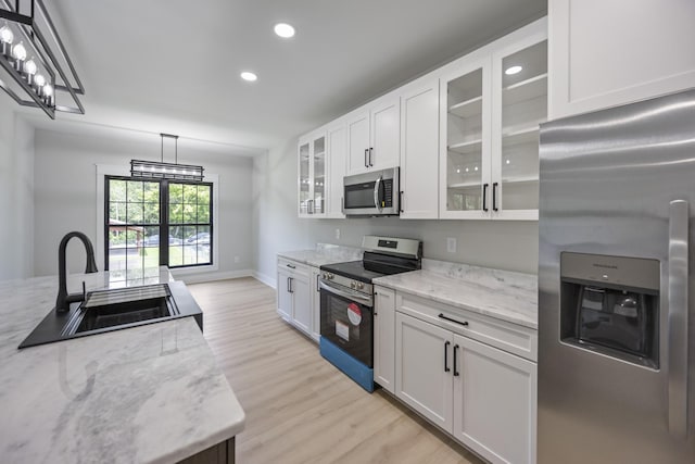 106 5th Ave N, Decherd, TN 37324 - kitchen with appliances with stainless steel finishes, light wood finished floors, hanging light fixtures, white cabinetry, and recessed lighting