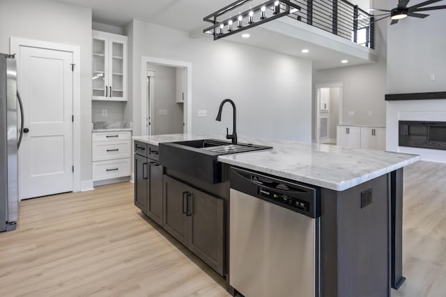106 5th Ave N, Decherd, TN 37324 - kitchen with appliances with stainless steel finishes, white cabinetry, an island with sink, light wood-style floors, and open floor plan