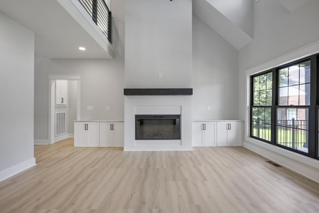 106 5th Ave N, Decherd, TN 37324 - unfurnished living room featuring a high ceiling, a glass covered fireplace, and light wood-style flooring