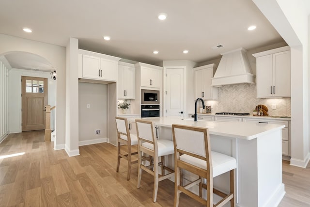 204 Phillips Bnd, Spring Hill, TN 37174 - kitchen with custom range hood, black oven, gas stovetop, arched walkways, and stainless steel microwave