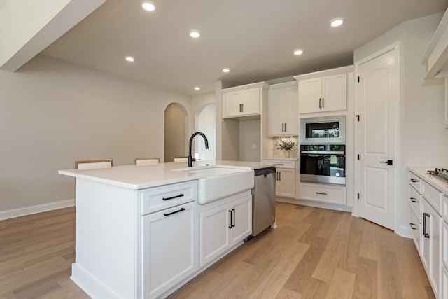 204 Phillips Bnd, Spring Hill, TN 37174 - kitchen featuring appliances with stainless steel finishes, arched walkways, light countertops, white cabinetry, and light wood-type flooring